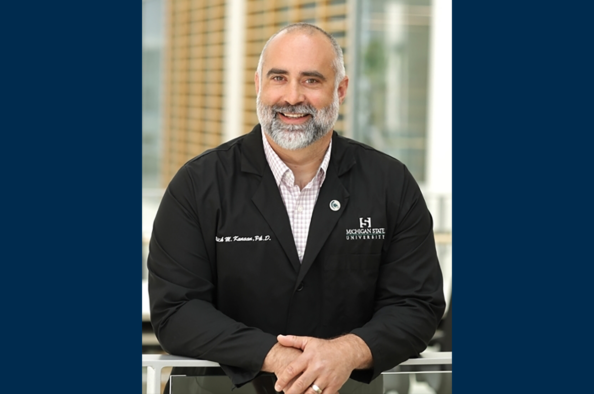 Photo of man in dark medical jacket leaning on railing